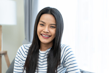 Portrait of Asian beautiful woman sit on sofa in living room at home.