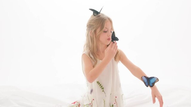 Portrait of a cute beautiful girl with butterflies in her hands on a white background in the studio.
