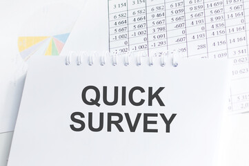 Quick Survey inscription on a notepad on the table next to reports and charts