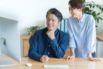 パソコンの前で話す二人の日本人男女