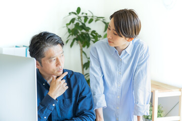 Fototapeta premium パソコンの前で話す二人の日本人男女