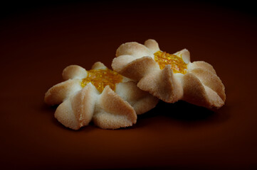 Two shortbread cookies on a dark red background . Kurabye cookies with jam . Beautiful cookies in the shape of a flower .