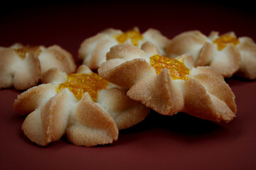 Several shortbread cookies in close-up on a red background . Kurabye cookies with jam . Beautiful cookies in the shape of a flower .