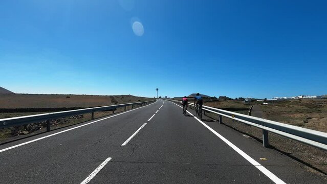 Group of cyclist rider enjoy sport leisure activity together training on the road. Concept of bikes and people rider outdoors. Blue sky in background. Long straight asphalt road. Scenic place. Pov
