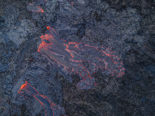 Lava flow from above. red hot magma flows from an active volcano on Iceland's Reykjanes Peninsula. structures in the black-blue rock. dark cooled magma around the lava flow