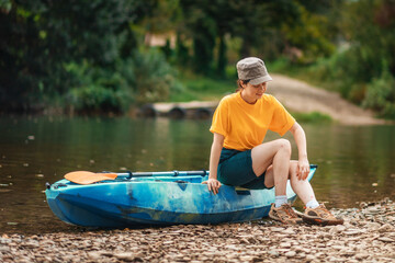 A young dissatisfied woman is sitting on a kayak and scratching her pimpled leg from a mosquito...