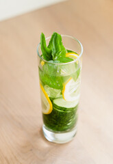 infused cucumber water in long glass.  summer drink with lemon and mint on light gray  concrete background. copy space