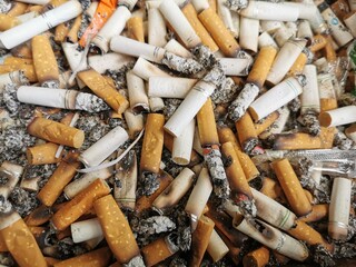 Lots of cigarette buds in a ash tray. Selective focus.