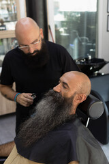 scene of a bald male client in a middle of a beard cut into a barbershop