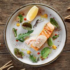 Plate of baked salmon fillet steak with lemon and herbs