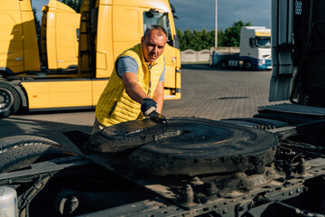 Fototapeta na wymiar A worker smearing trailer fifth wheel coupling with lubricant oil. Semi-truck mechanical maintenance 