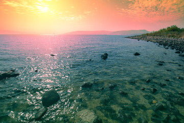 Rocky shore of the Sea of Galilee at sunrise - obrazy, fototapety, plakaty