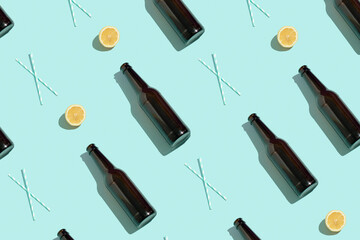 Pattern with brown beer bottles, halves of fresh lemon and drinking straws on blue background....