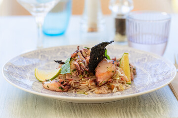 Pan-fried squid and flavored rice in oriental style with lime slices and basil leaves