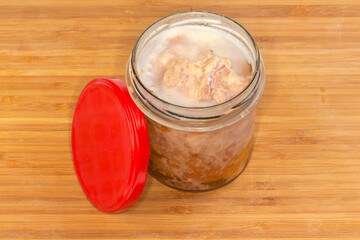 Braised pork in open small jar on a wooden surface