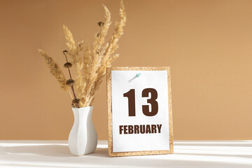 february 13. 13th day of month, calendar date.White vase with dried flowers on desktop in rays of sunlight on white-beige background. Concept of day of year, time planner, winter month