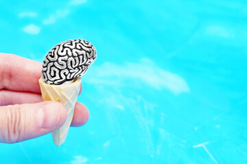 Human brain figurine in a waffle cone on blue