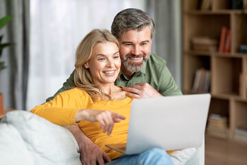 Beautiful Middle Aged Couple With Laptop Computer Resting Together At Home