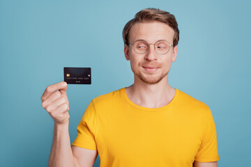 Curious smart guy financier showing plastic debit card wear casual clothes isolated on turquoise background