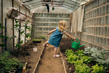Little blonde girl gardening in the greenhouse