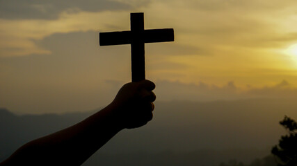 Shadow of a man holding a cross in the evening sunlight