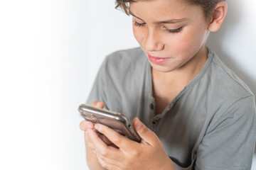 Portrait of smiling young boy holds mobile phone with copy space.