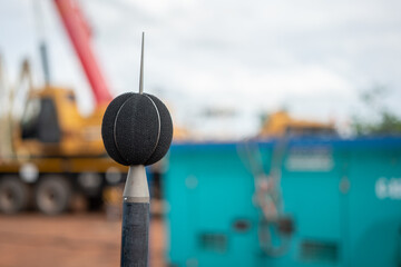 A sound recording equipment using to measuring noise level with blurred background of construction working place. Close-up and selective focus at the equipment part.
