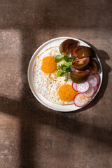 Fried eggs with fresh tomatoes on a white plate on a wooden table