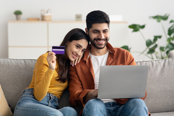 Couple Shopping Online Making Payment With Card Using Laptop Indoors