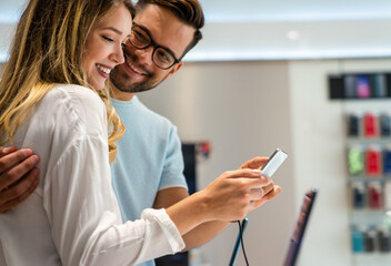 Shopping a new digital device. Happy couple buying a smartphone in store.