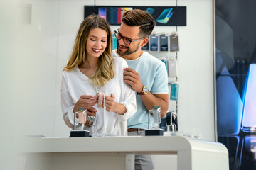 Obraz premium Happy young people buying new digital gadgets in store. Tecgnology smart watch shopping concept