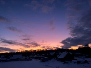 Small village in winter against the background of a fabulous sunset.