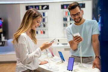 Happy young people buying new smartphone in mobile shop. Technology device shopping concept