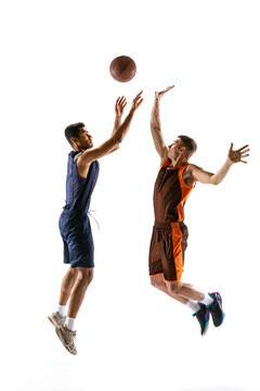 Full-length portrait of two young men, professional basketball players in motion, training isolated over white studio background. Jump shot