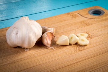 Uncut and sliced garlic on a bamboo wooden cutting board
