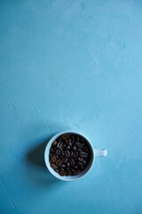 ziarna kawy w białej filiżance na niebieskim tle 