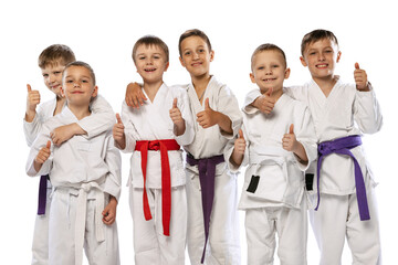 Group of happy children, beginner karate fighters in white doboks standing together isolated on white background. Concept of sport, martial arts, education - obrazy, fototapety, plakaty