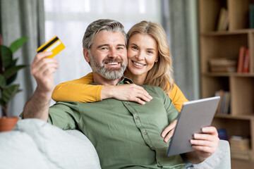 Online Payments. Smiling Middle Aged Spouses Holding Credit Card And Digital Tablet