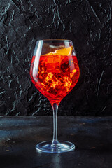 Aperol cocktail with a fresh orange, a side view on a black background, Italian summer cold drink