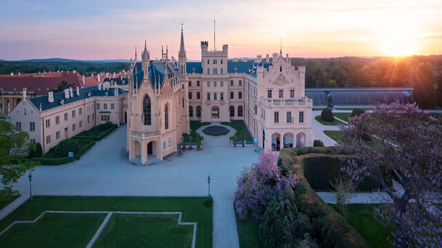 Aerial, panoramic view of Lednice Castle, Moravia, Czechia. Famous tourist spot. Fairytale castle in a baroque garden, lit by the morning sun. UNESCO cultural heritage. Spring season, no people.