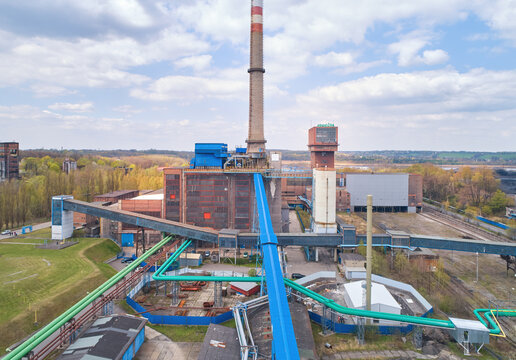 The area of the coal power plant after the end of operation in the spring landscape. Brick building, blue technical installations and conveyors. Aerial views. Coal exit program. Drone inspection.