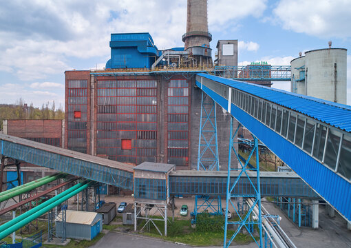 The area of the coal power plant after the end of operation in the spring landscape. Brick building, blue technical installations and conveyors. Aerial views. Coal exit program. Drone inspection.