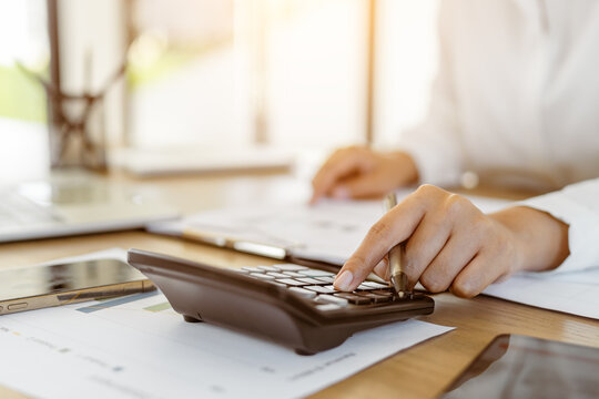 Close up hands of business calculating financial data report of company with calculator.