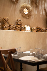 Interior with food table, decorative items made of wicker on the wall and the dining table out of focus