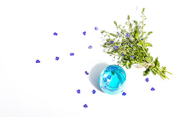 Cold tonic water and blue forget me not flowers bouquet on trendy stand isolated on white background