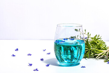 Cold tonic water and blue forget me not flowers bouquet on trendy stand isolated on white background