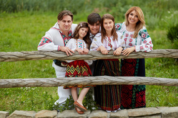 Happy family with kids in traditional romanian dress in a countryside, park. Father, mother, son and daughters posing outside.