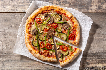 Vegetarian pizza with zucchini, tomato, peppers and mushrooms on wooden table	