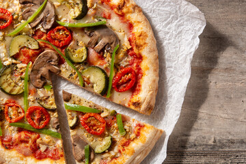 Vegetarian pizza with zucchini, tomato, peppers and mushrooms on wooden table	