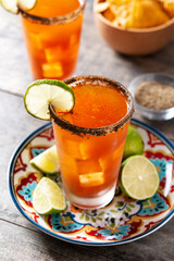 Homemade michelada cocktail with beer, lime juice,hot sauce,salted rim and tomato juice on wooden table